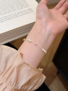 Close-up detail of a S925 sterling silver bracelet with delicate freshwater pearls on a wrist