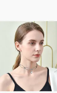 Detailed view of a minimalist silver metal heart pendant necklace on a model's neck