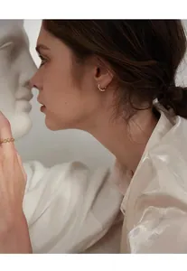 Close-up of elegant gold Mobius hoop earrings worn by a model in artistic setting