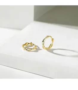 Close-up detail of golden Mobius hoop earrings featuring a polished twisted texture