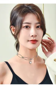 Detailed view of a silver minimalist metal choker featuring a dangling heart pendant