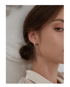 Detail shot of elegant minimalist sterling silver Mobius hoop earrings worn by a model