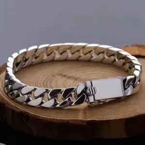 Detail view of a polished S925 silver Cuban link bracelet on a rustic wooden base