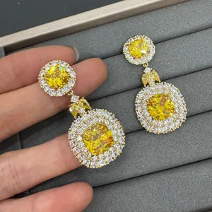Detailed macro view of luxury yellow cushion-cut zircon dangling earrings on gray tray