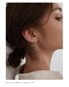 Close-up detail of a twisted silver Mobius hoop earring on a model's ear