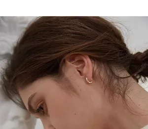 Close-up of a gold Mobius hoop earring worn by a model in a side profile view.