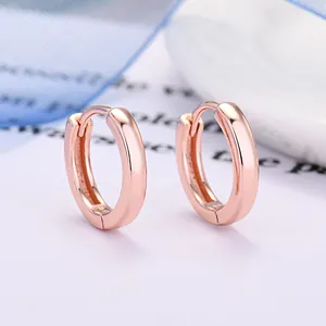 Primo piano dettagliato di orecchini a cerchio in oro rosa lucido con superficie liscia