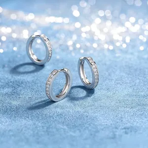 Macro detail of S925 silver moissanite hoop earrings on sparkling blue background