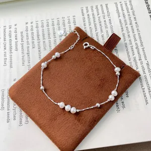 Detail shot of S925 silver bracelet with natural freshwater pearls on brown pouch.