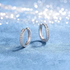 Detailed macro shot of elegant silver moissanite hoop earrings on blue texture
