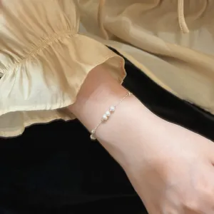 Minimalist S925 sterling silver bracelet with natural freshwater pearls on model's wrist.
