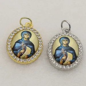Detailed view of two oval micro-pave religious icon charms in gold and silver