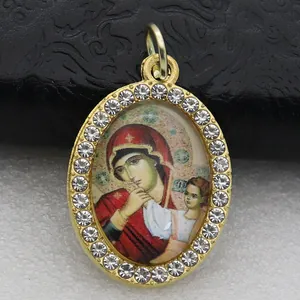 Detailed close-up of an oval religious icon pendant with a micro-pave rhinestone frame