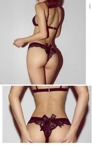 Detail view of black lace thong featuring a silk bow and intricate hollow-out patterns