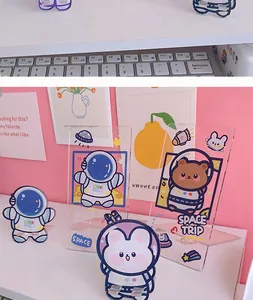 Detailed view of cute rabbit and bear astronaut acrylic phone stands on a white desk.
