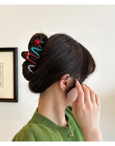 Detailed visual of a large wave-patterned shark hair clip worn by a model in a casual setting