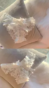 Detail view of white lace panties with large satin bow and delicate embroidery.