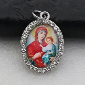 Detailed view of oval silver-tone pendant featuring Virgin Mary and Child with rhinestones