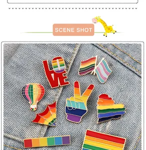 Close-up of vibrant rainbow enamel pins featuring love, flags, and peace signs on denim.
