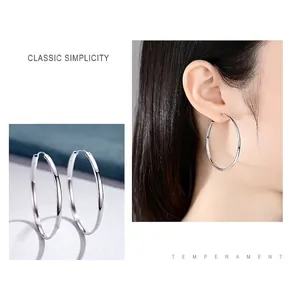 Vue détaillée de grandes créoles polies en argent sterling 999 portées par le mannequin