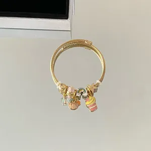 Vue détaillée d'un bracelet câble torsadé doré avec des pendentifs en émail