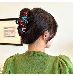 Close-up view of a stylish multi-colored wavy shark hair claw clip worn on a bun hairstyle