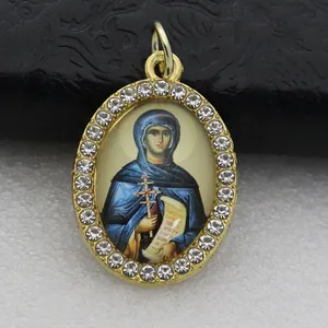 Detailed macro shot of an oval religious pendant with gold-tone rhinestone frame.