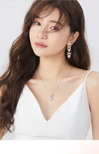 Primo piano di una modella con collana a cuore rosa e fiocco d'argento con orecchini abbinati