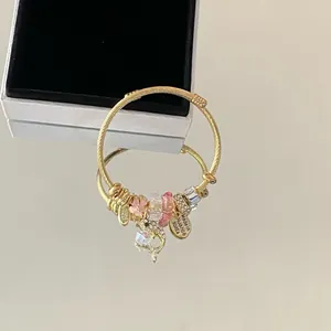 Gros plan d'un bracelet à breloques en acier doré avec cristaux roses et médaillon