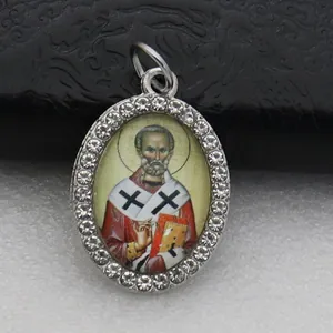 Macro detail of oval micro-pave pendant with religious saint icon and crystals