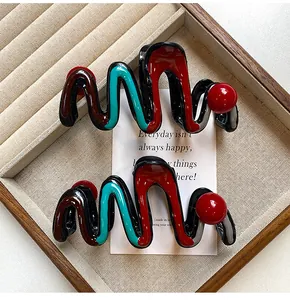Detailed macro shot of red and teal wavy large hair claw clips displayed in jewelry tray