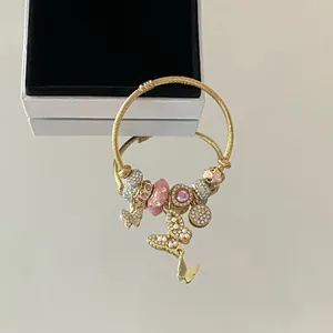 Gros plan d'un bracelet à breloques doré avec cristaux roses et pendentifs papillon