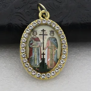 Close-up detail of an oval golden pendant featuring micro-pave rhinestones and religious icon