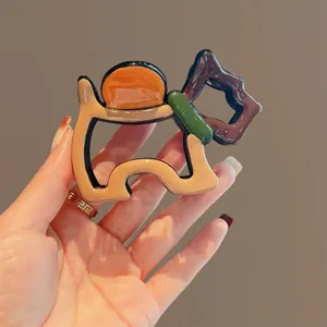 Detail view of a large dog-shaped hair claw clip with colorful resin design.