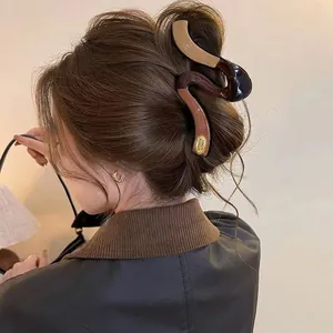Detailed view of a large brown and dark blue hair claw clip used in a stylish bun.