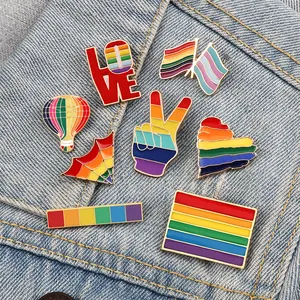 Colorful rainbow enamel lapel pins set displayed on denim jacket pocket background.