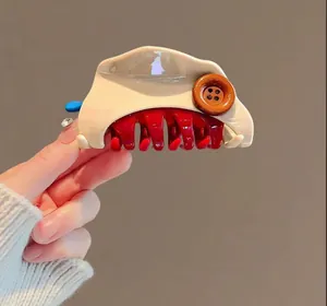 Detailed view of large shark hair clip with cream and red color block design