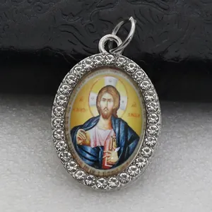 Detailed view of an oval pendant featuring a religious icon framed with rhinestones