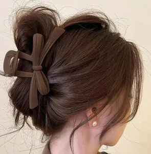 Elegant large matte brown bow hair claw clip shown on a woman's brown hair updo