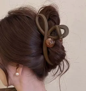 Close-up of a large matte brown shark hair claw clip with an amber marble bead detail