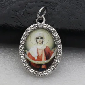 Detailed close-up of an oval rhinestone-paved pendant with a religious icon portrait.