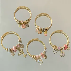 Set de cinq bracelets à breloques en acier doré avec cristaux roses et fil métal