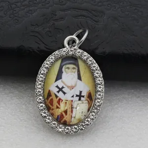 Close-up macro view of an oval religious saint pendant with shiny rhinestone border.