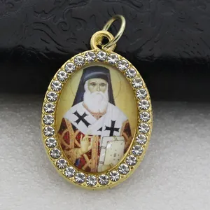 Detail of an oval golden pendant with religious icon and rhinestone border.