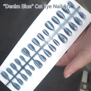 Detailed macro shot of short almond press-on nails featuring a denim blue cat-eye effect