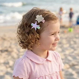 Little girl on beach wearing cute turtle and starfish hair clips detail
