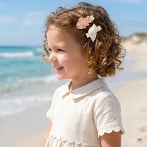 Toddler girl wearing cute ocean-themed glitter fish and shell hair clips while at the beach
