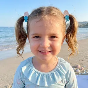 Cute mermaid hair clips for girls featuring blue glitter tail worn at the beach