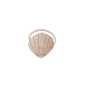 Detail of a cute champagne gold PU leather shell ornament on a flexible hair tie