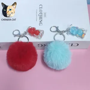 Dettaglio di portachiavi a pompon con ciondoli a forma di orso su sfondo rosa tenue.